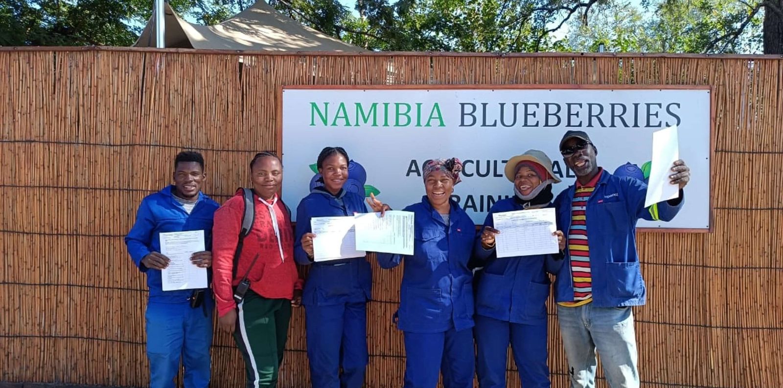Teilnehmende mit ihren Zertifikaten vor dem Schild des landwirtschaftlichen Schulungszentrums von Namibia Blueberries